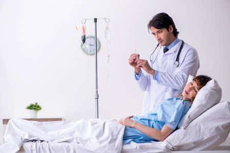 Male doctor visiting female patient in wardの写真素材