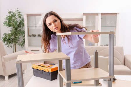 Young woman repairing chair at homeの写真素材