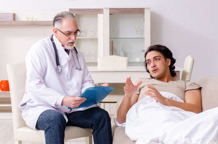 Old male doctor visiting young male patientの写真素材