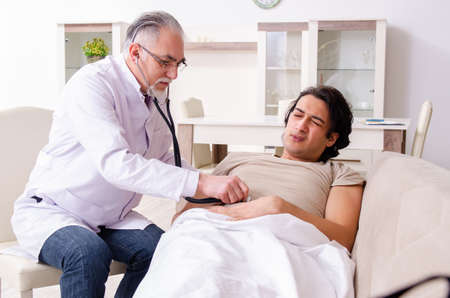 Old male doctor visiting young male patientの写真素材