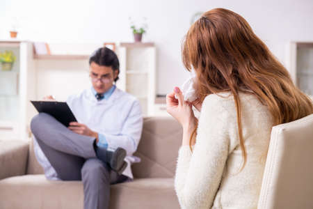 Young female patient discussing with male psychologist personalの写真素材