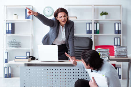 Old female boss and young male employee in the officeの写真素材
