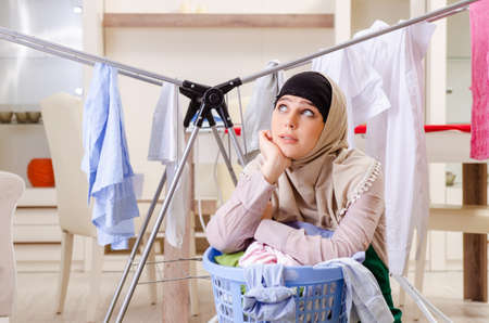 Woman in hijab doing clothing ironing at homeの写真素材
