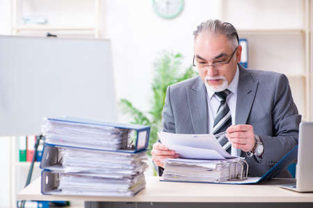 Aged male employee unhappy with excessive workの写真素材