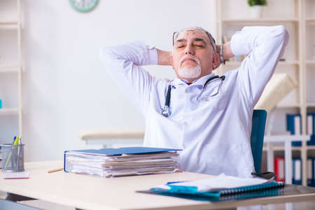 Old male doctor working in the clinicの写真素材