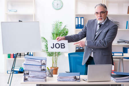 Aged male employee unhappy with excessive workの写真素材
