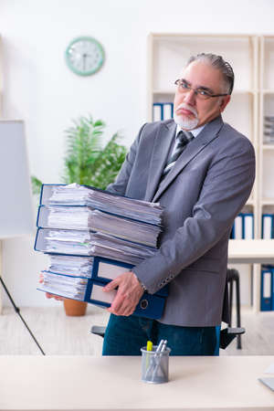 Aged male employee unhappy with excessive workの写真素材