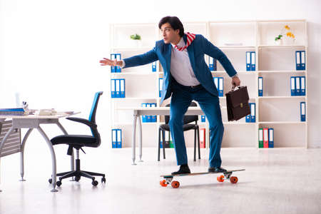 Young handsome businessman with longboard in the officeの写真素材