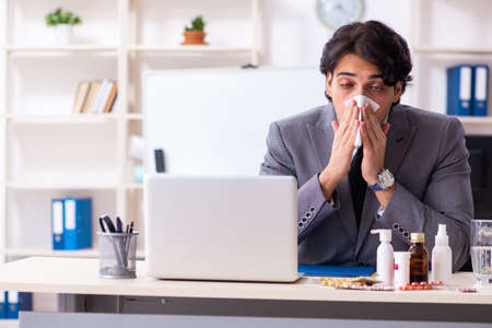 Man with flu working in the officeの写真素材