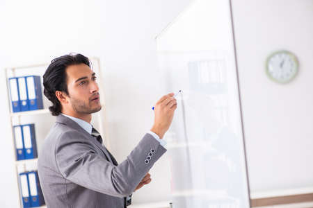 Young handsome businessman in front of whiteboardの写真素材