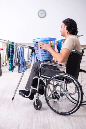 Young man in wheel-chair doing ironing at homeの写真素材