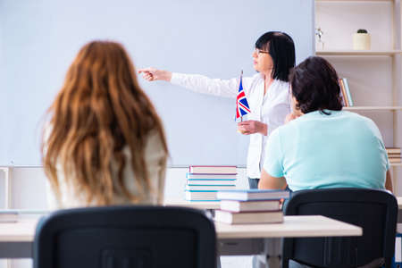 Old female english teacher and students in the classroomの写真素材