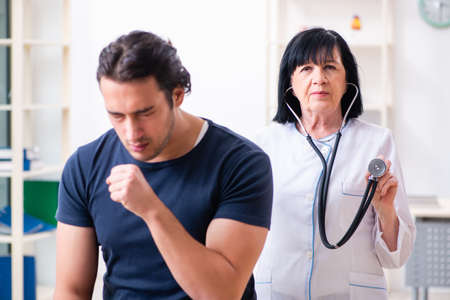 Young male patient visiting aged female doctorの写真素材