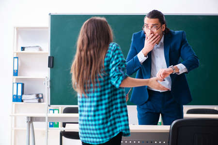 Young handsome teacher and female student in the classroomの写真素材
