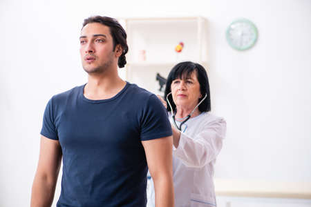 Young male patient visiting aged female doctorの写真素材