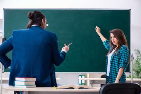 Young handsome teacher and female student in the classroom