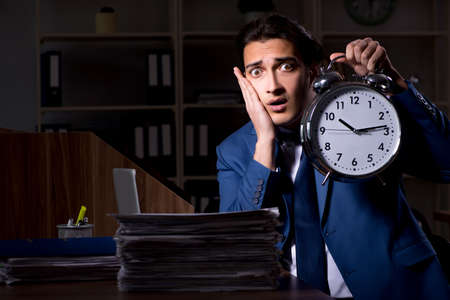 Young male employee working night in the officeの写真素材