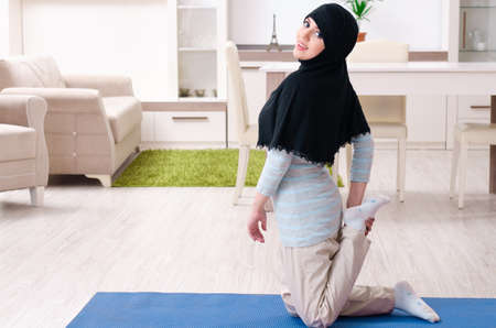 Young woman in hijab doing exercises at homeの写真素材