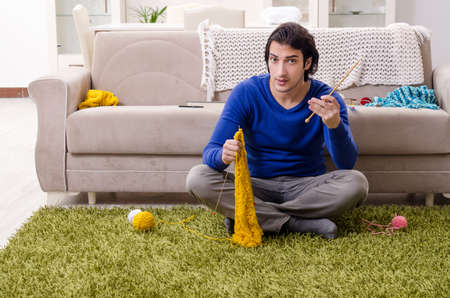 Young good looking man knitting at homeの写真素材