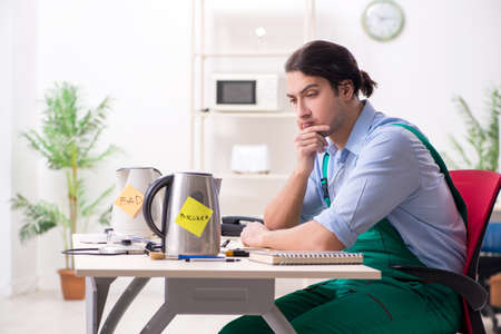 Young man repairing kettle in service centreの写真素材