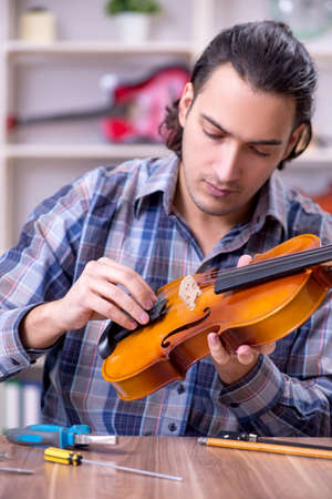 Young handsome repairman repairing violinの写真素材