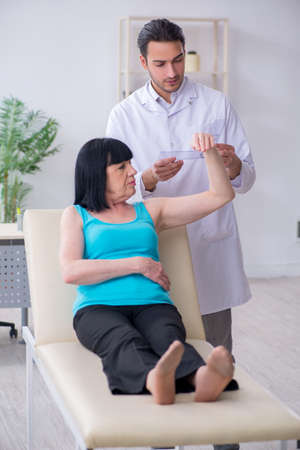 Young male doctor examining old female patientの写真素材