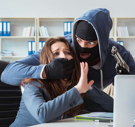 Criminal taking businesswoman as hostage in officeの写真素材