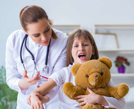 Woman female doctor examining little cute girl with toy bear
