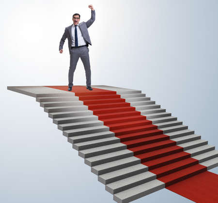 Young businessman climbing stairs and red carpetの写真素材