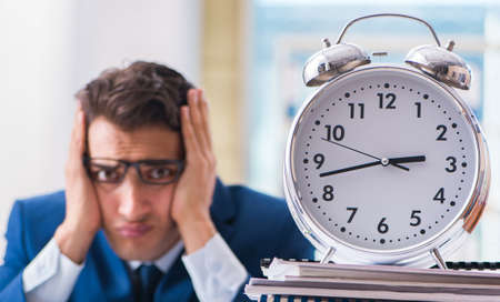 Businessman with giant clock failing to meet deadlines and missionの写真素材