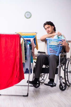 Young man in wheel-chair doing ironing at homeの写真素材