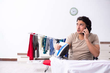 Young man in wheel-chair doing ironing at homeの写真素材