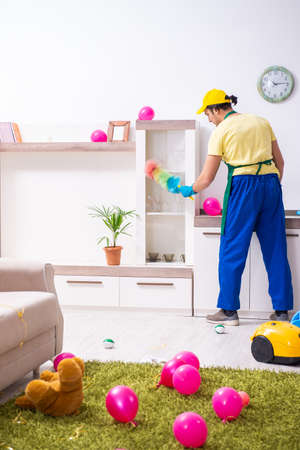 Young male contractor doing housework after partyの写真素材