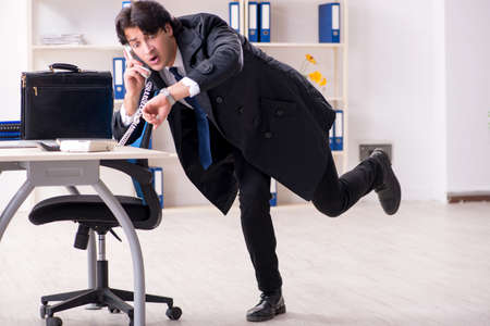 Young male employee in the office in time management conceptの写真素材