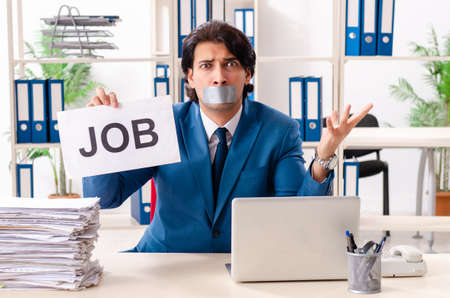 Young male employee with tape on the mouthの写真素材