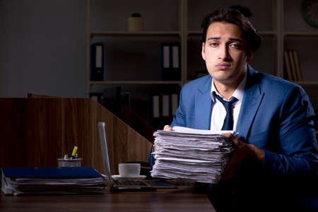 Young male employee working night in the officeの写真素材