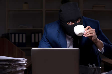 Male employee stealing information in the office night timeの写真素材