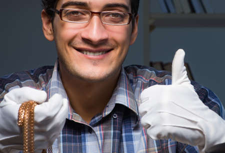 Young male jeweller working at night in his workshopの写真素材