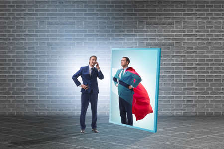 Businessman seeing himself in mirror as superheroの写真素材