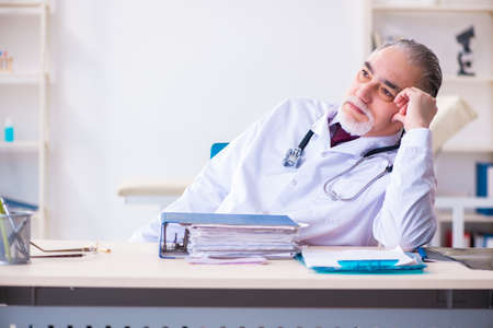 Old male doctor working in the clinicの写真素材