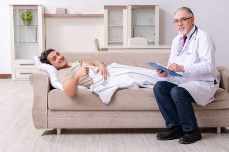 Old male doctor visiting young male patientの写真素材