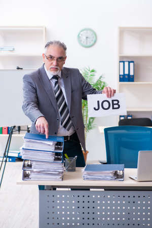 Aged male employee unhappy with excessive workの写真素材
