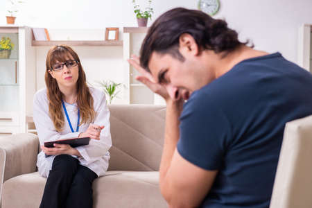 Young male patient discussing with female psychologist personalの写真素材