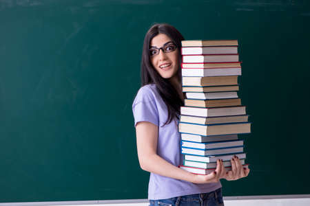 Young female teacher student in front of green boardの写真素材