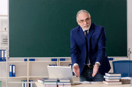 Aged male teacher in front of chalkboardの写真素材