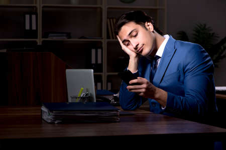 Young male employee working night in the officeの写真素材
