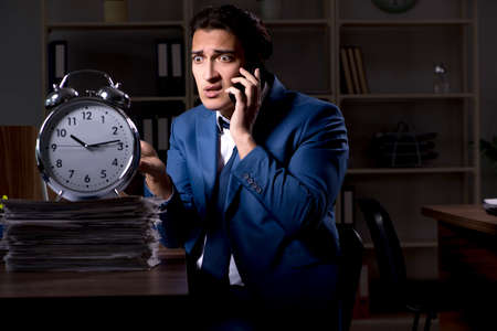 Young male employee working night in the officeの写真素材