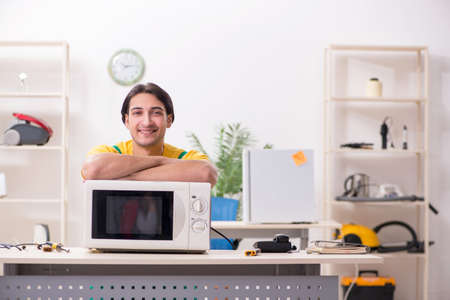 Young repairman repairing microwave in service centreの写真素材