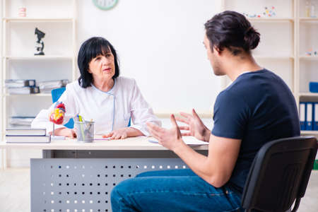 Young male patient visiting aged female doctorの写真素材