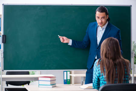 Young handsome teacher and female student in the classroomの写真素材